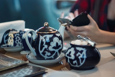 People sitting in front of white and red ceramic tea set
